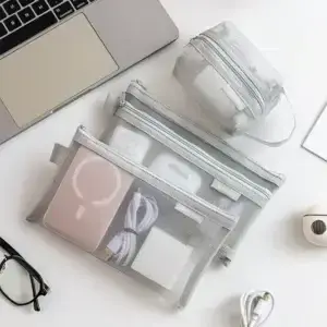 Grey mesh travel organizer pouches beside a laptop for small accessories and travel items