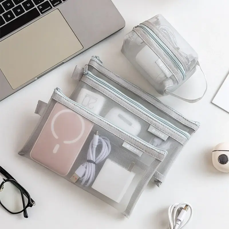Grey mesh travel organizer pouches beside a laptop for small accessories and travel items