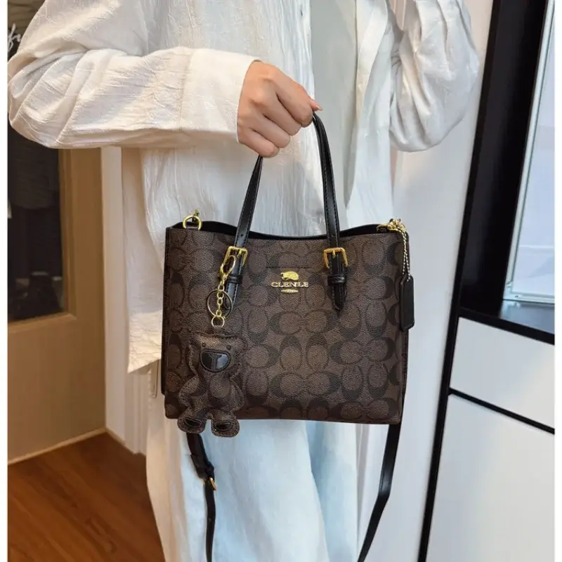 Person in a light shirt holding a brown printed tote bag by its dark handles