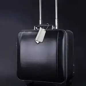 Silver aluminum luggage tag attached to a black suitcase for travel identification