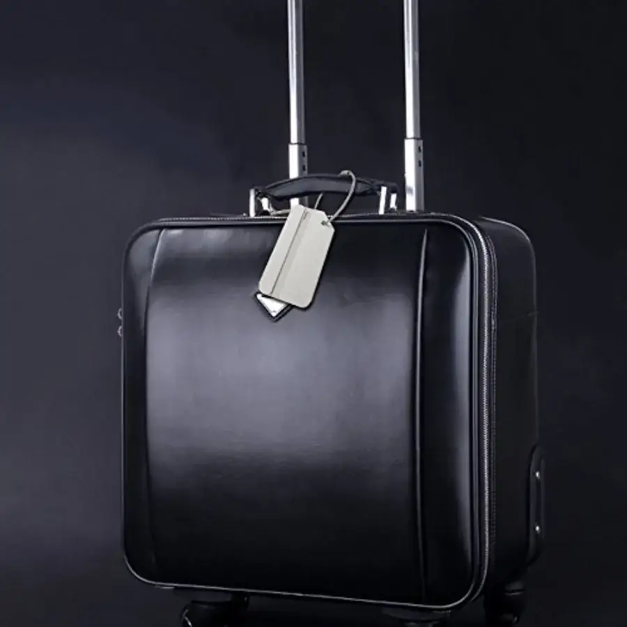 Silver aluminum luggage tag attached to a black suitcase for travel identification