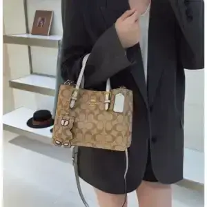 Person in dark clothing carrying a tan printed tote bag with dark handles