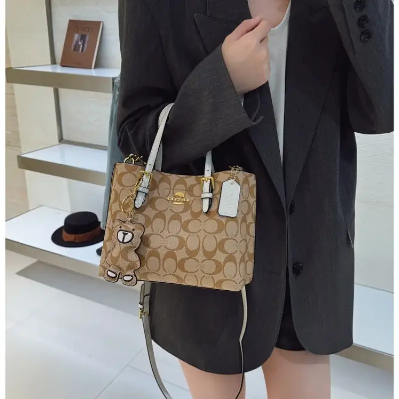 Person in dark clothing carrying a tan printed tote bag with dark handles