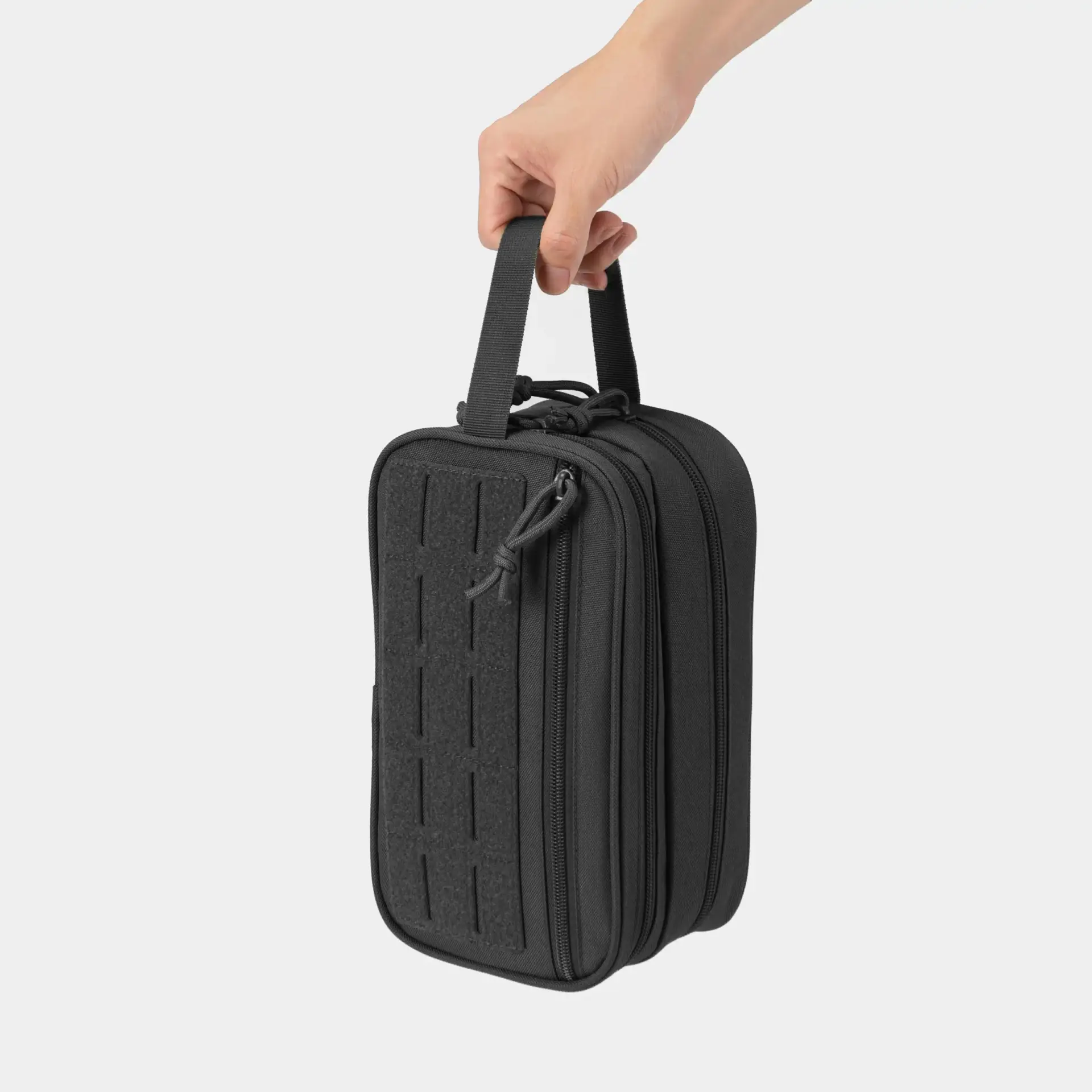Hand holding a black zippered organizer pouch by its webbing handle