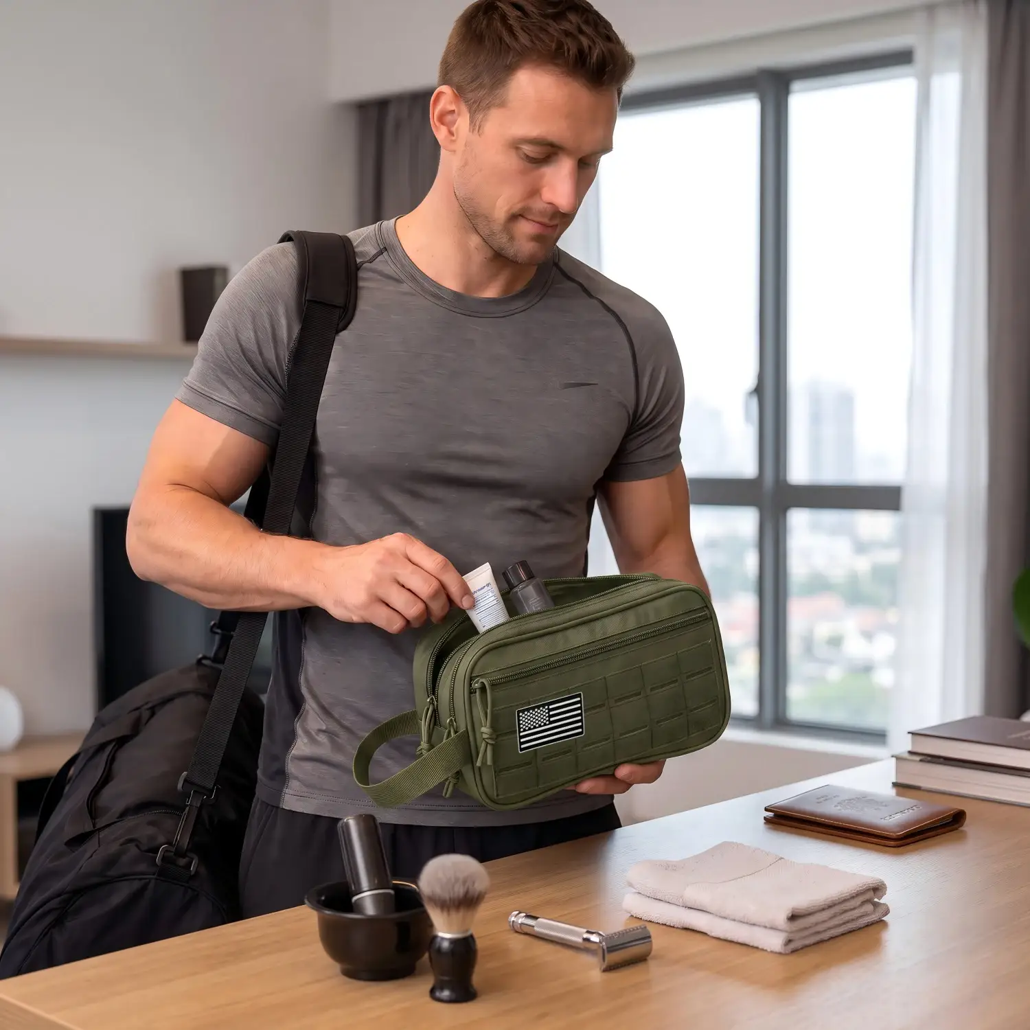 Man placing a bottle into an olive green toiletry organizer beside shaving items and towels